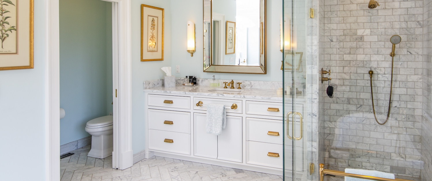 https://walkerwoodworking.com/wp-content/uploads/2020/08/Walker-Woodworking-custom-cabinets-inset-white-bathroom-cabinets-brass-hardware-bathroom-tile-walk-in-shower-master-bathroom-1500x630.jpg