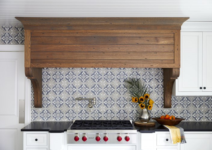 kitchen range hood made from quarter sawn white oak surrounded by white kitchen cabinets