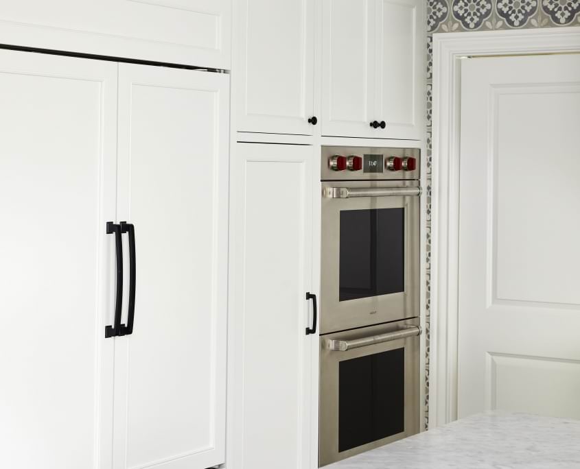 White kitchen cabinets with a double wall oven and light countertop