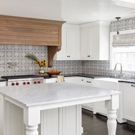 white traditional style kitchen with black countertops and custom wood hood