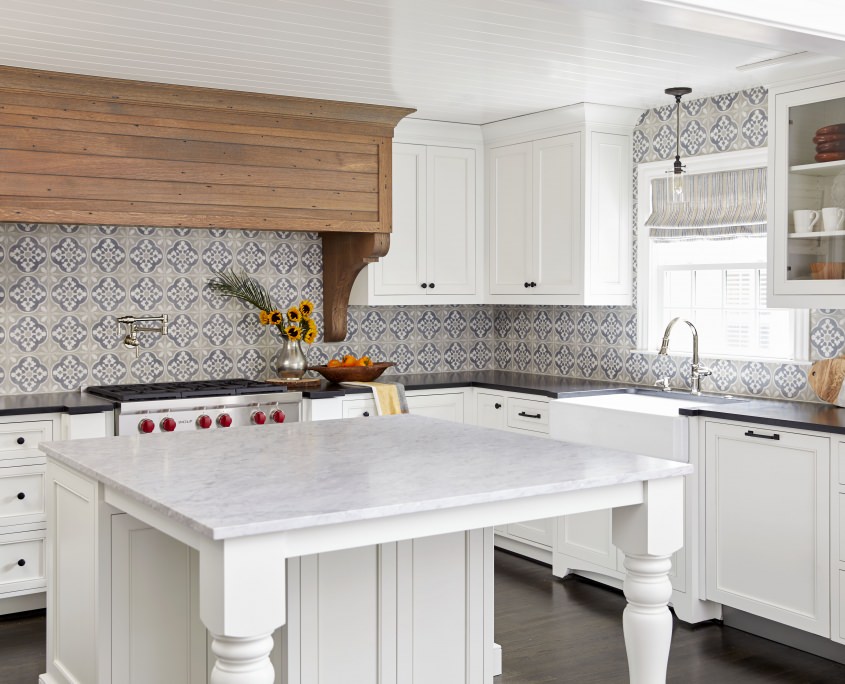 white traditional style kitchen with black countertops and custom wood hood