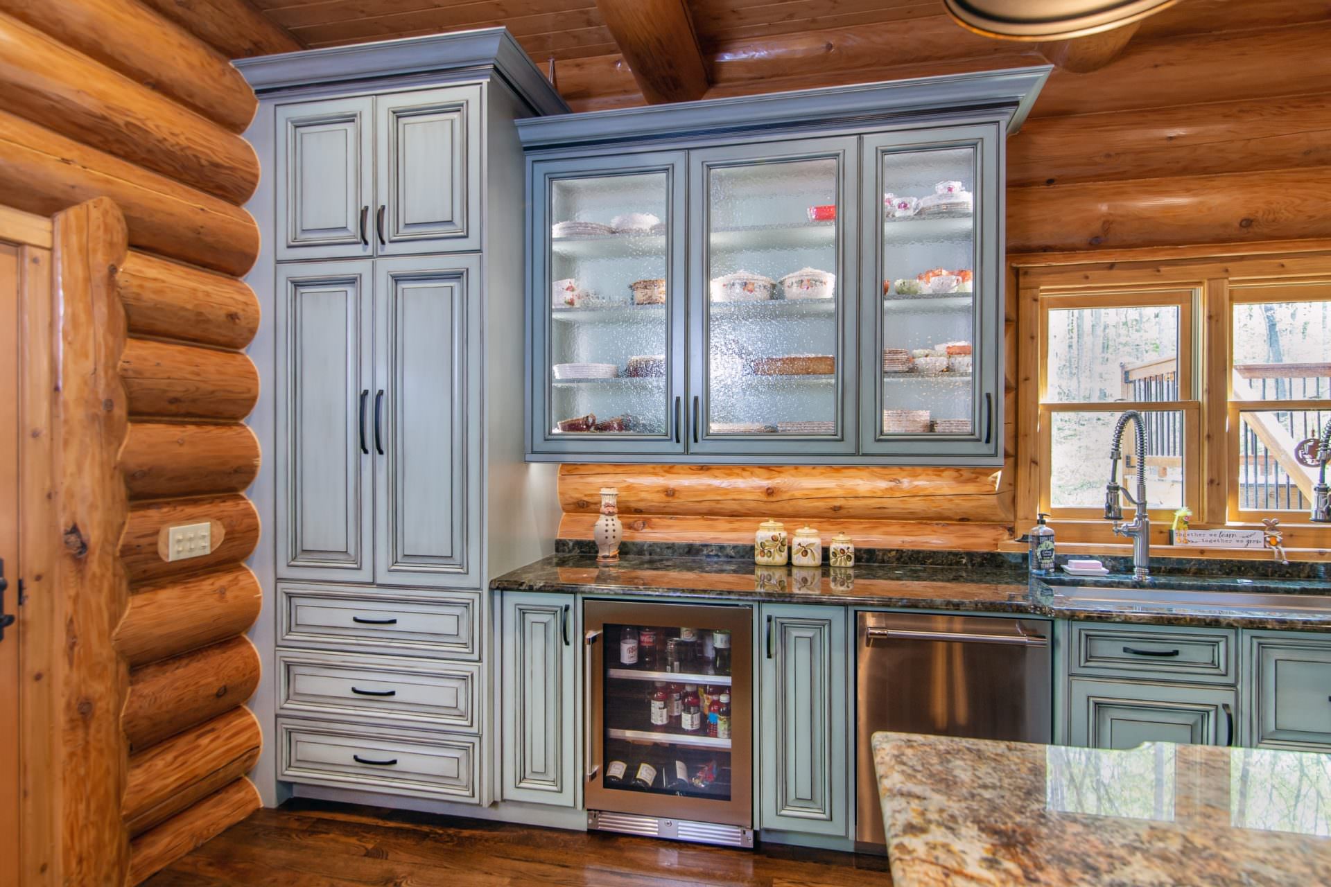 https://walkerwoodworking.com/wp-content/uploads/2021/05/Walker-Woodworking-custom-cabinets-glass-front-cabinet-beverage-cooler-light-blue-kitchen-cabinets-glazed-cabinets-scaled.jpg