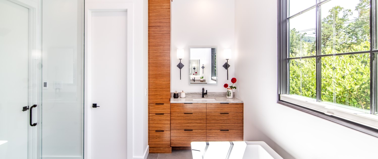 https://walkerwoodworking.com/wp-content/uploads/2022/10/Walker-woodoworking-custom-cabinets-master-bathroom-vanity-tub-shower-lighting-zebrawood-veneer-cabinets-frameless-1500x630.jpg