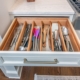 A kitchen with a custom white cabinet drawer pulled out full of organized utensils