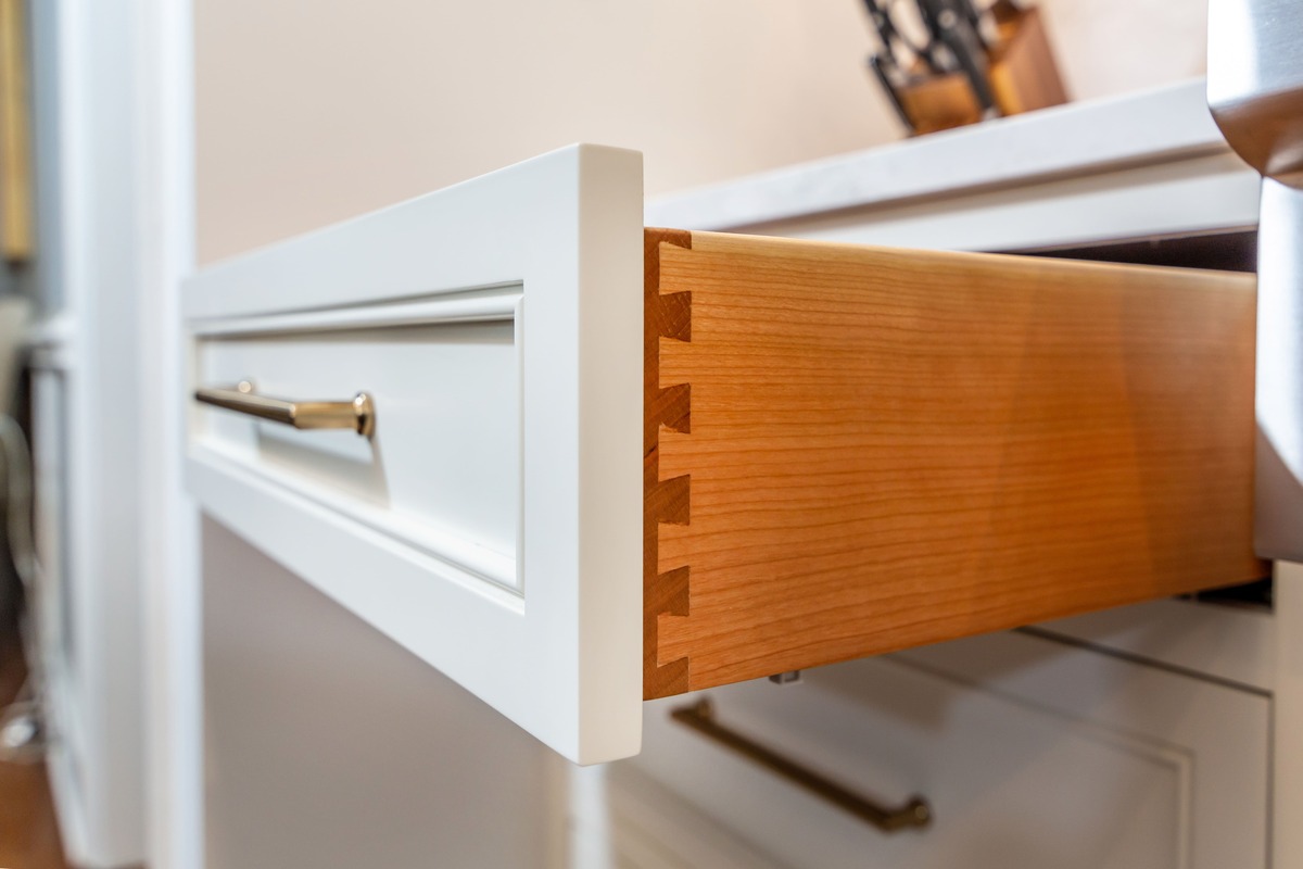 A kitchen with a white cabinet drawer pulled out and shown up close