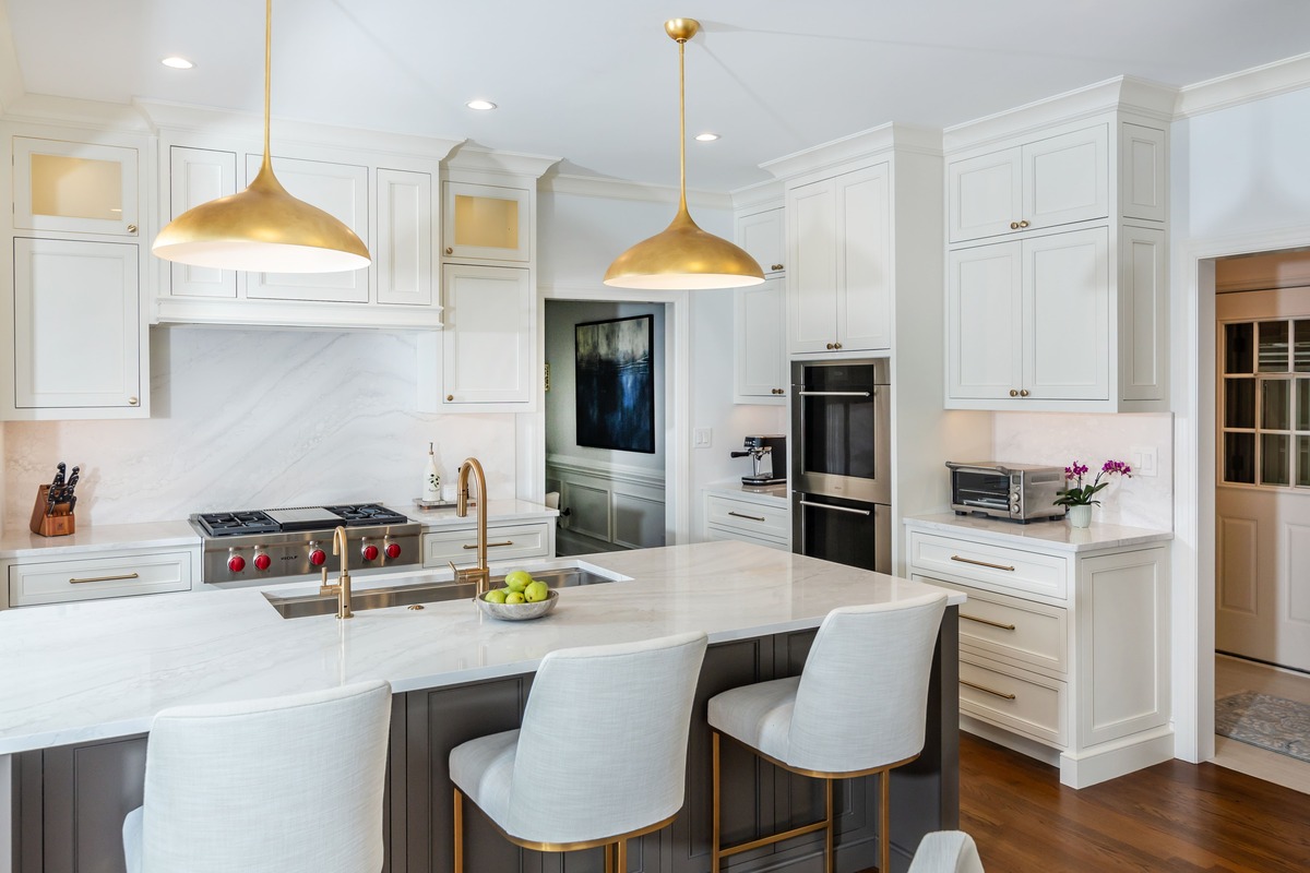 A white kitchen with cabinets and drawers with gold lighting and wood flooring