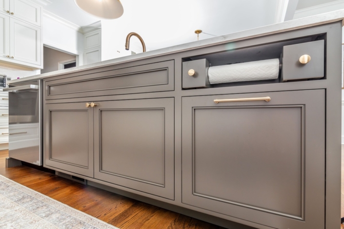 A kitchen with grey cabinetry and a large island countertop with a paper towel holder