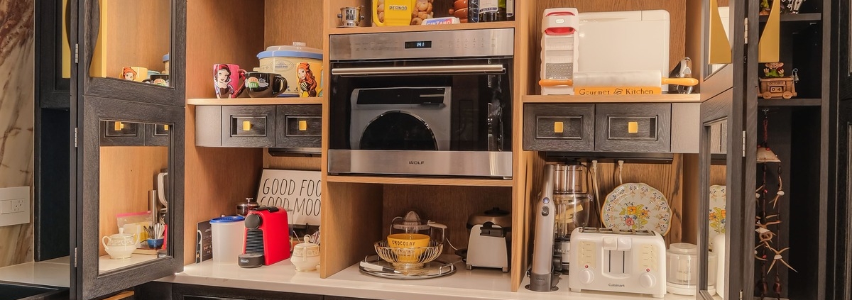 A butler pantry with custom oak cabinetry and a built in small oven and coffee maker