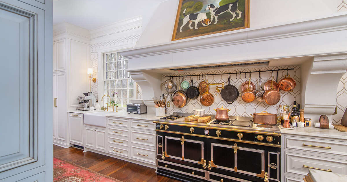 White kitchen with a large hood and pots and pans