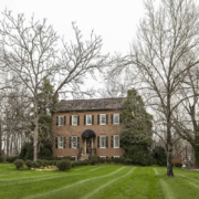 Historical home with black shutters and large trees