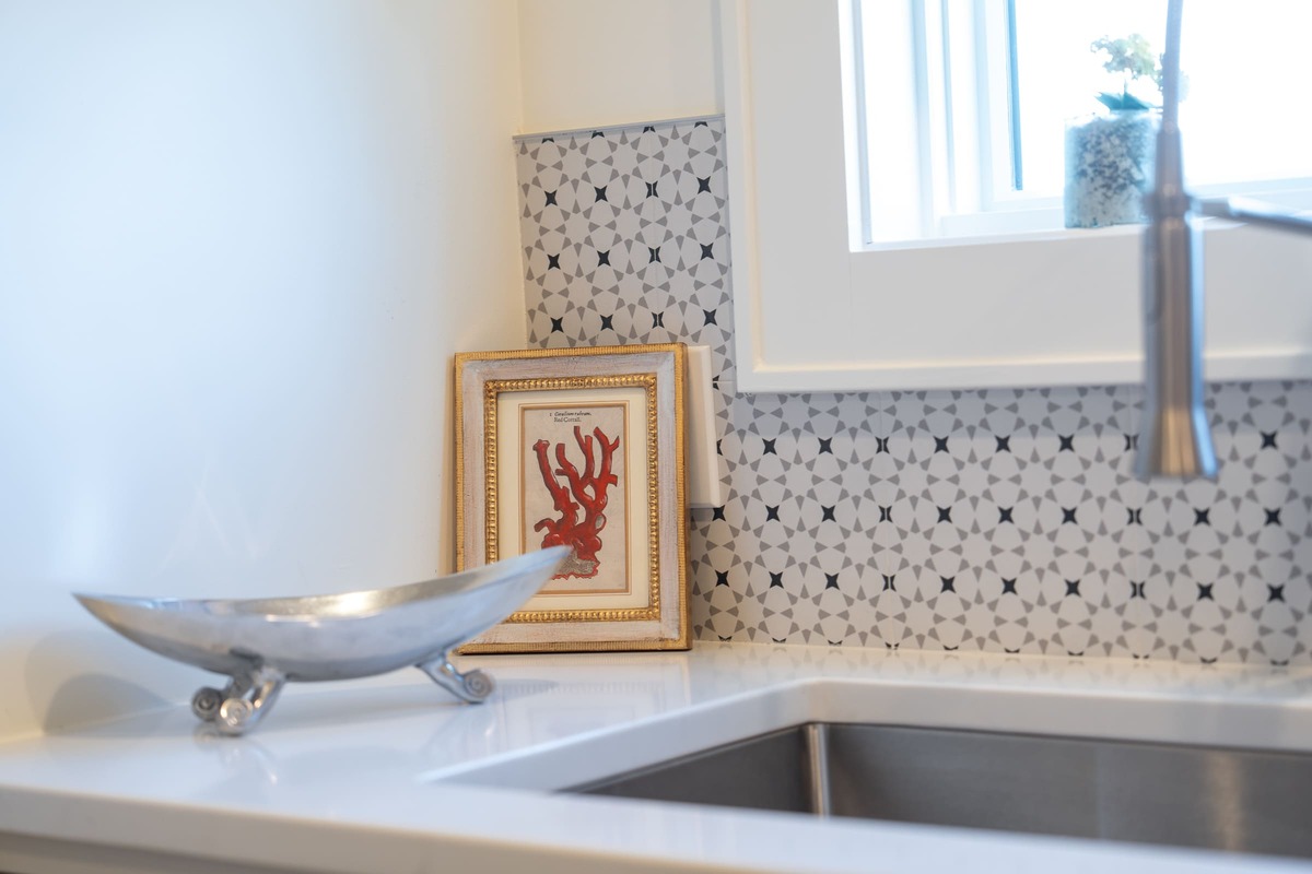 A laundry room with a custom designed backsplash and a silver soap dish with a sink