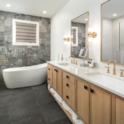 A large bathroom with wooden cabinets and a large bathtub with tile flooring and mirrors