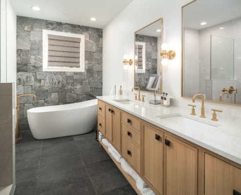 A large bathroom with wooden cabinets and a large bathtub with tile flooring and mirrors
