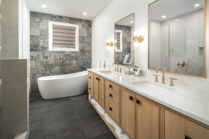 A large bathroom with wooden cabinets and a large bathtub with tile flooring and mirrors