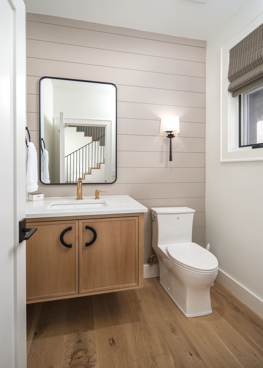 A bathroom with a floating vanity cabinet countertop a toilet and with wood flooring