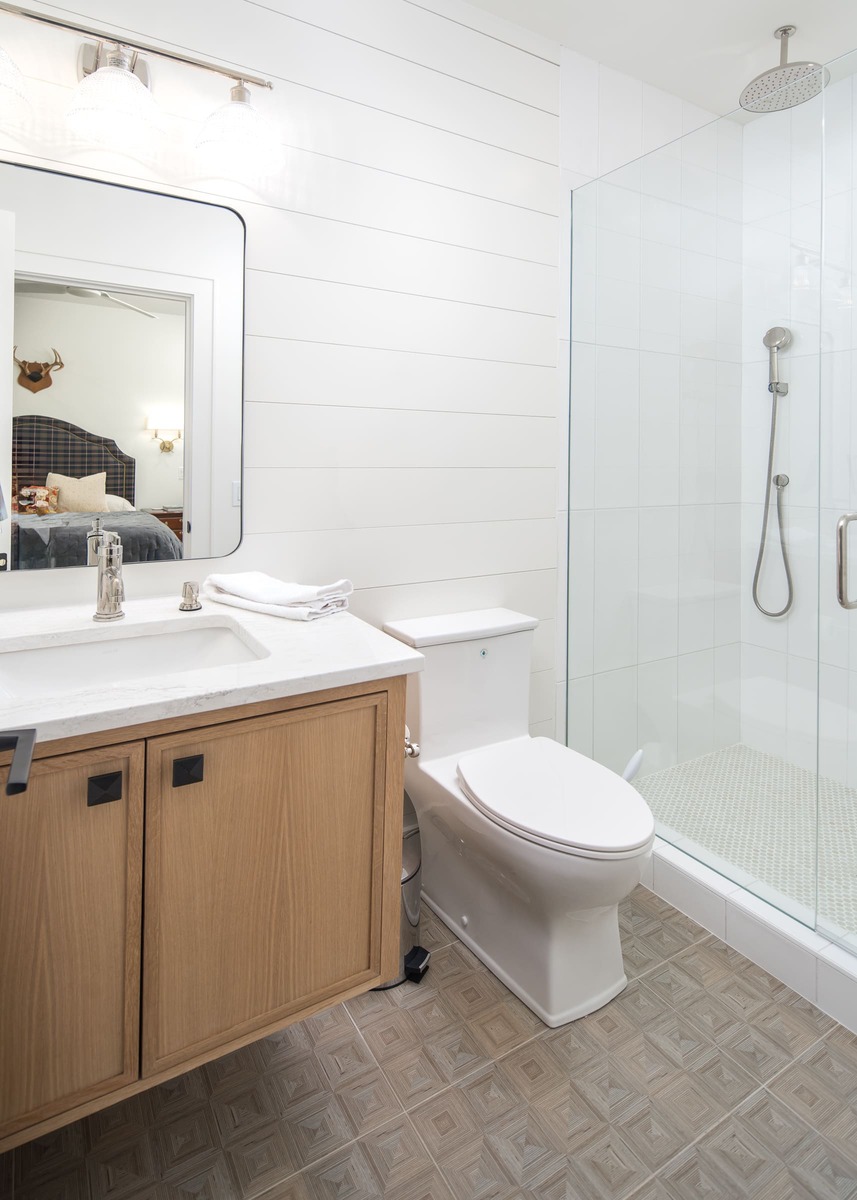 A bathroom with a floating vanity cabinet and stone tile flooring with a white backsplash