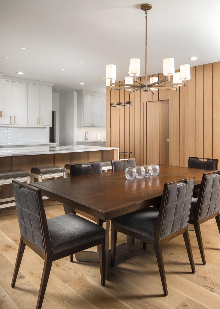 A large kitchen with white cabinets and a large kitchen table with wood flooring