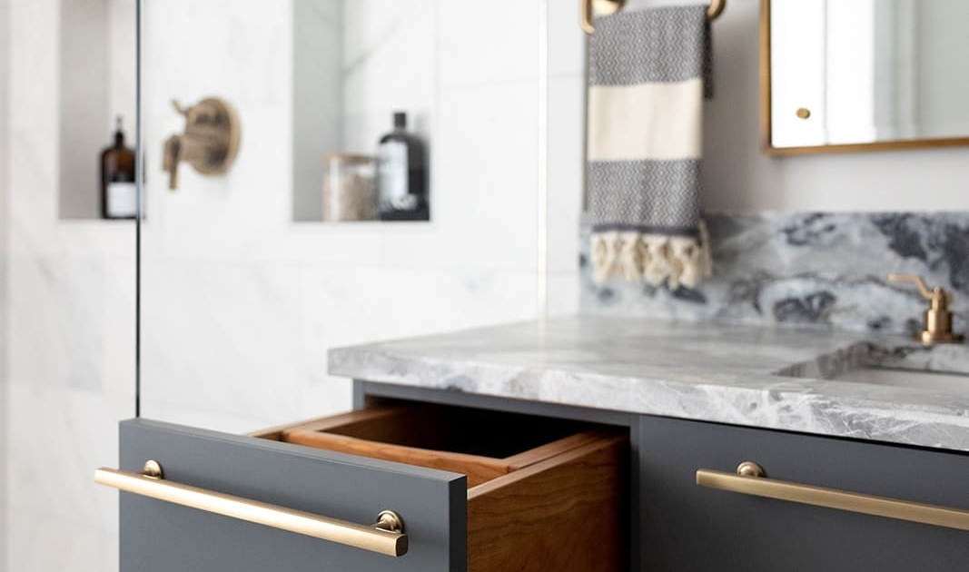 A bathroom with a floating vanity with gray cabinetry and a drawer pulled open
