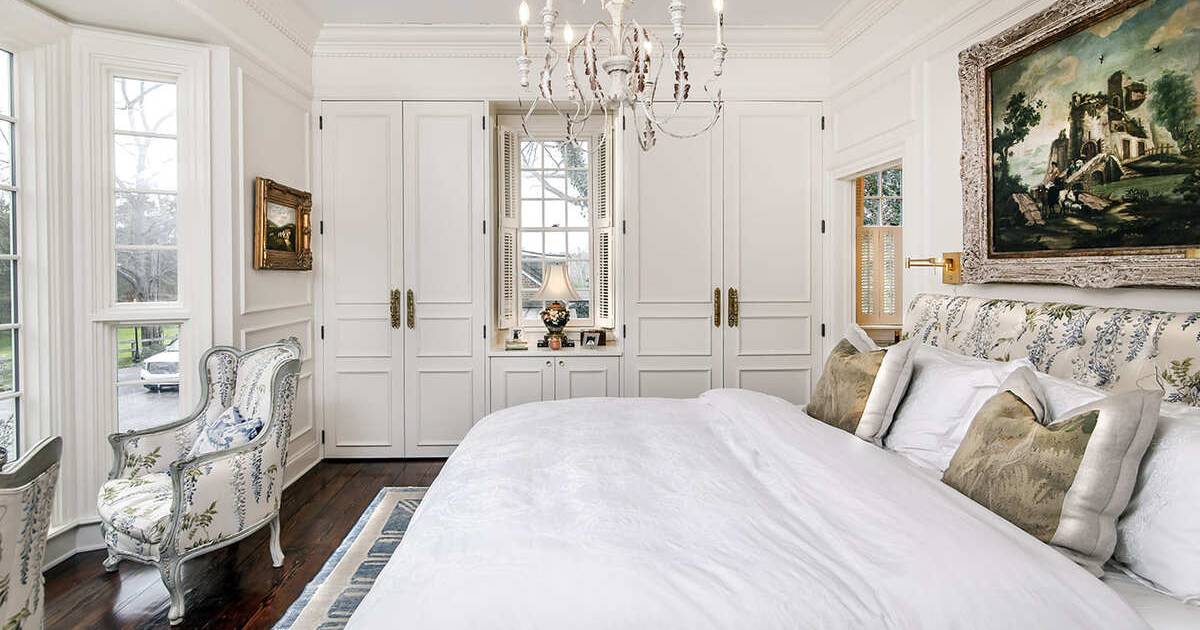 A master bedroom with white cabinetry and a built in closet on both sides and a white bed