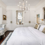 A master bedroom with white cabinetry and a built in closet on both sides and a white bed