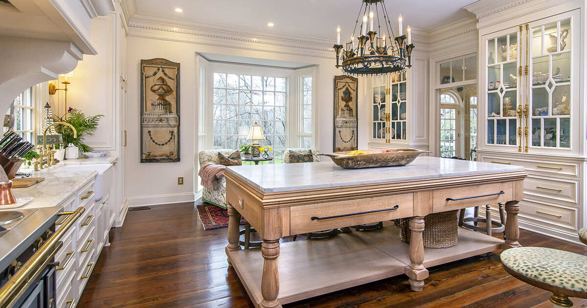 Large kitchen island with white countertops and a kitchen hutch