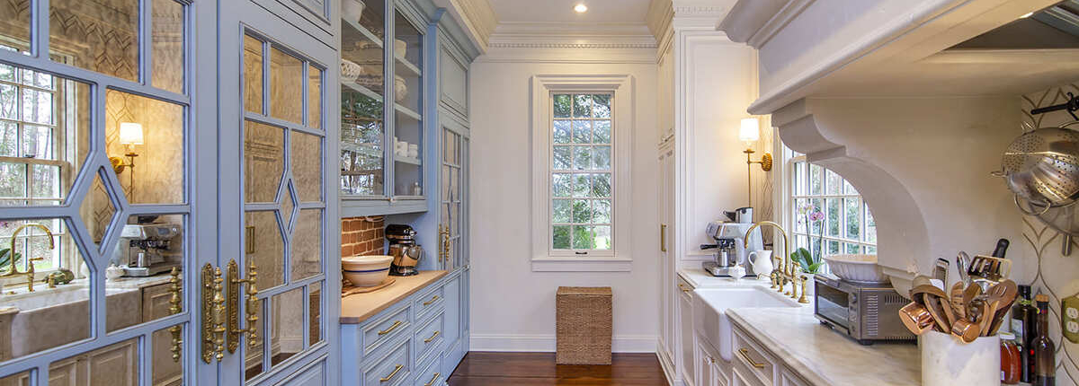 A kitchen with blue and white cabinets with gold hardware and a farmhouse sink