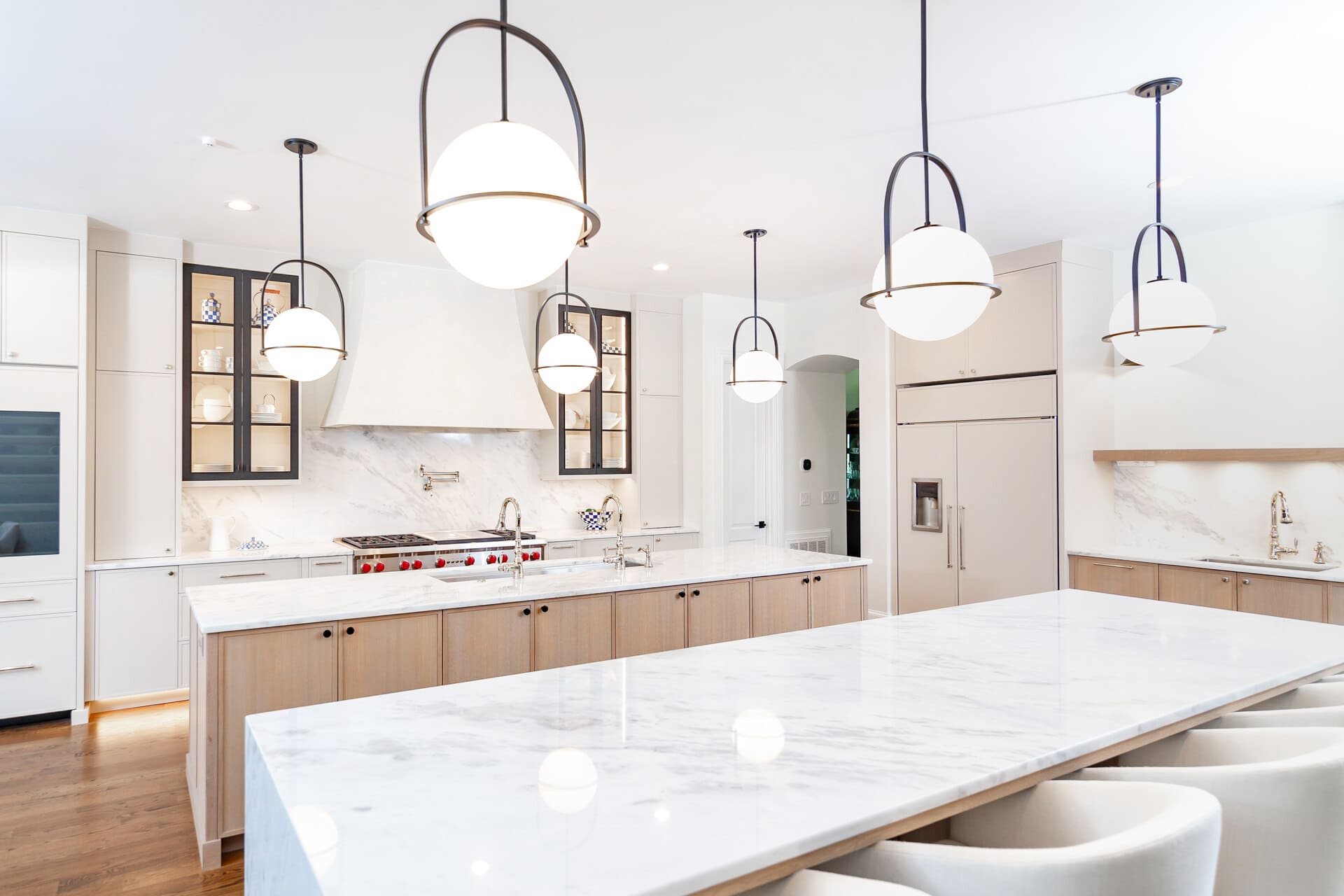 A white kitchen with a double island and white and brown cabinets and a rangehood