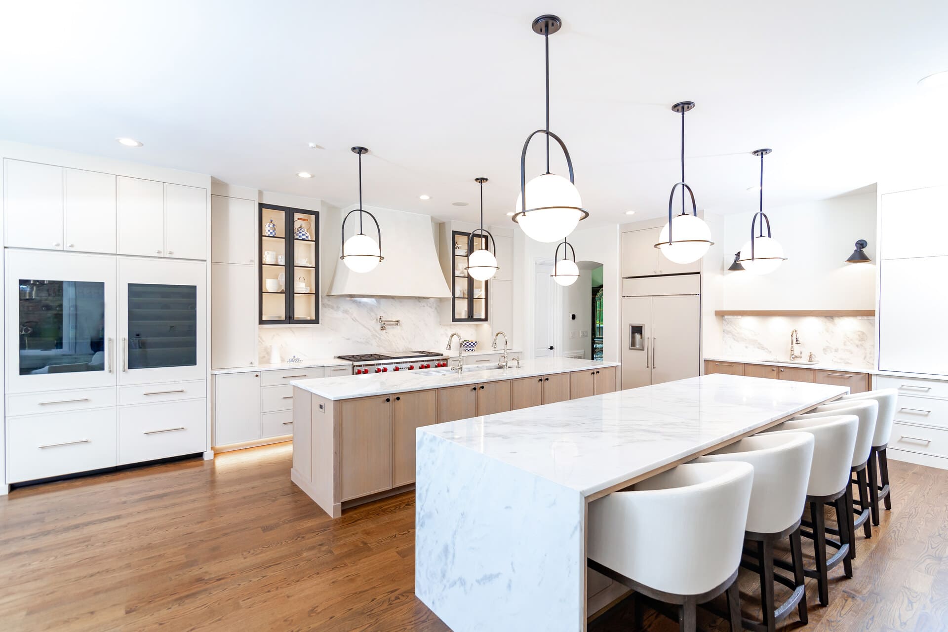 A white kitchen with frameless cabinets and a double island countertop with lighting
