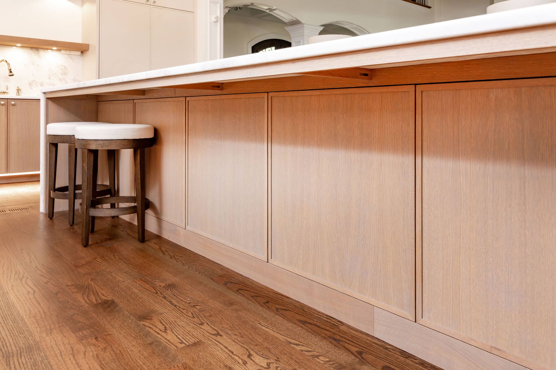 A kitchen with oak frameless push to open cabinets and a double island with bar stools