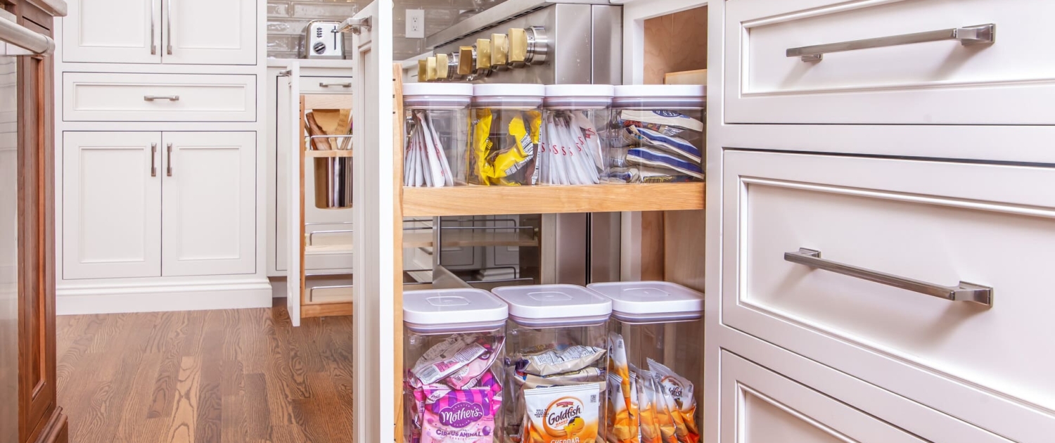 A kitchen with a pull out cabinet drawer open showing storage containers neatly inside