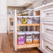 A kitchen with a pull out cabinet drawer open showing storage containers neatly inside