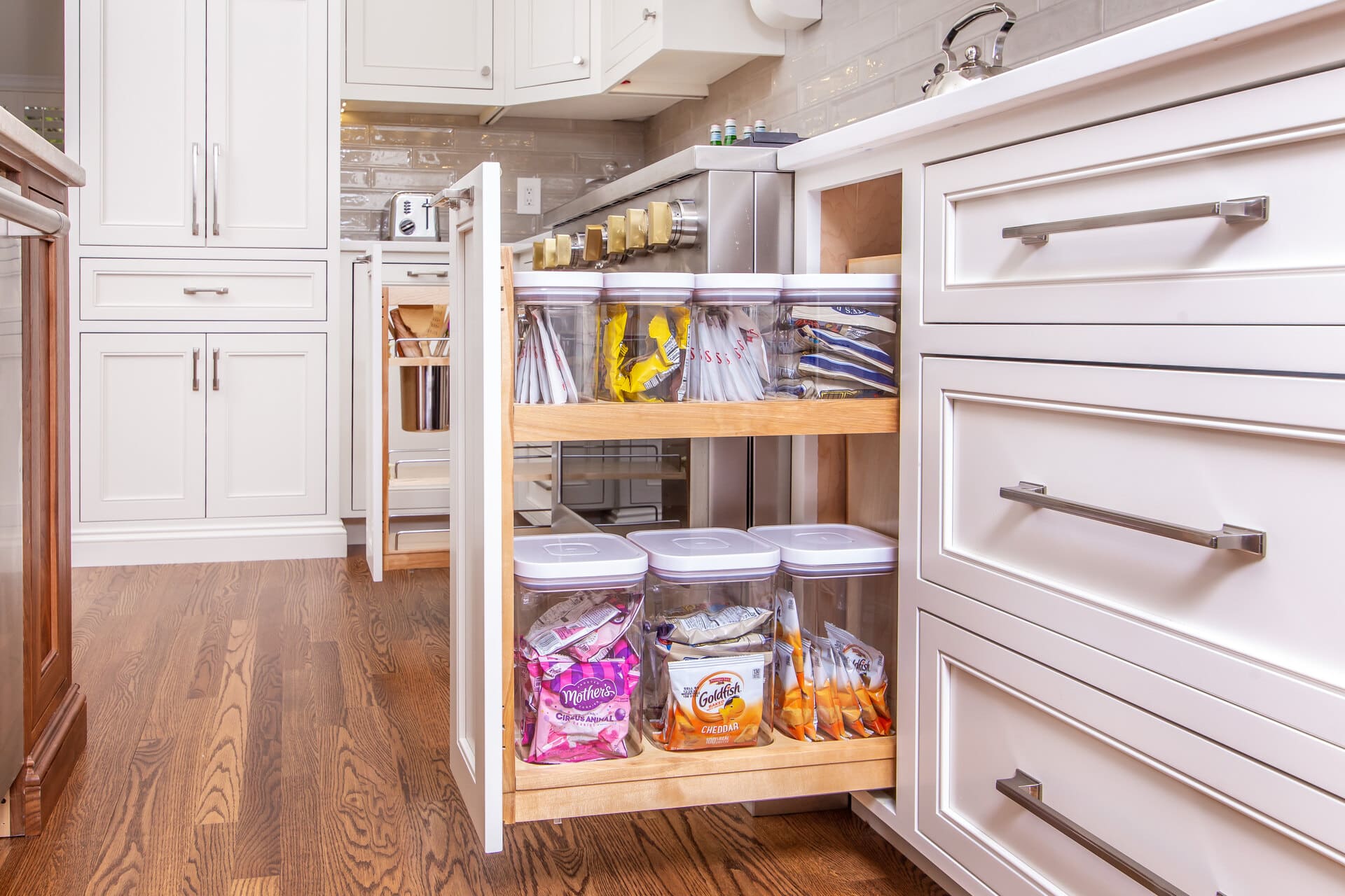 A kitchen with a pull out cabinet drawer open showing storage containers neatly inside