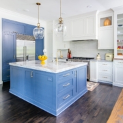 A kitchen with white and blue cabinetry and glass front doors