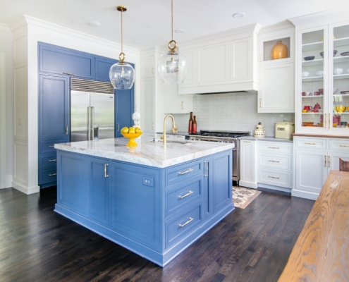 A kitchen with white and blue cabinetry and glass front doors