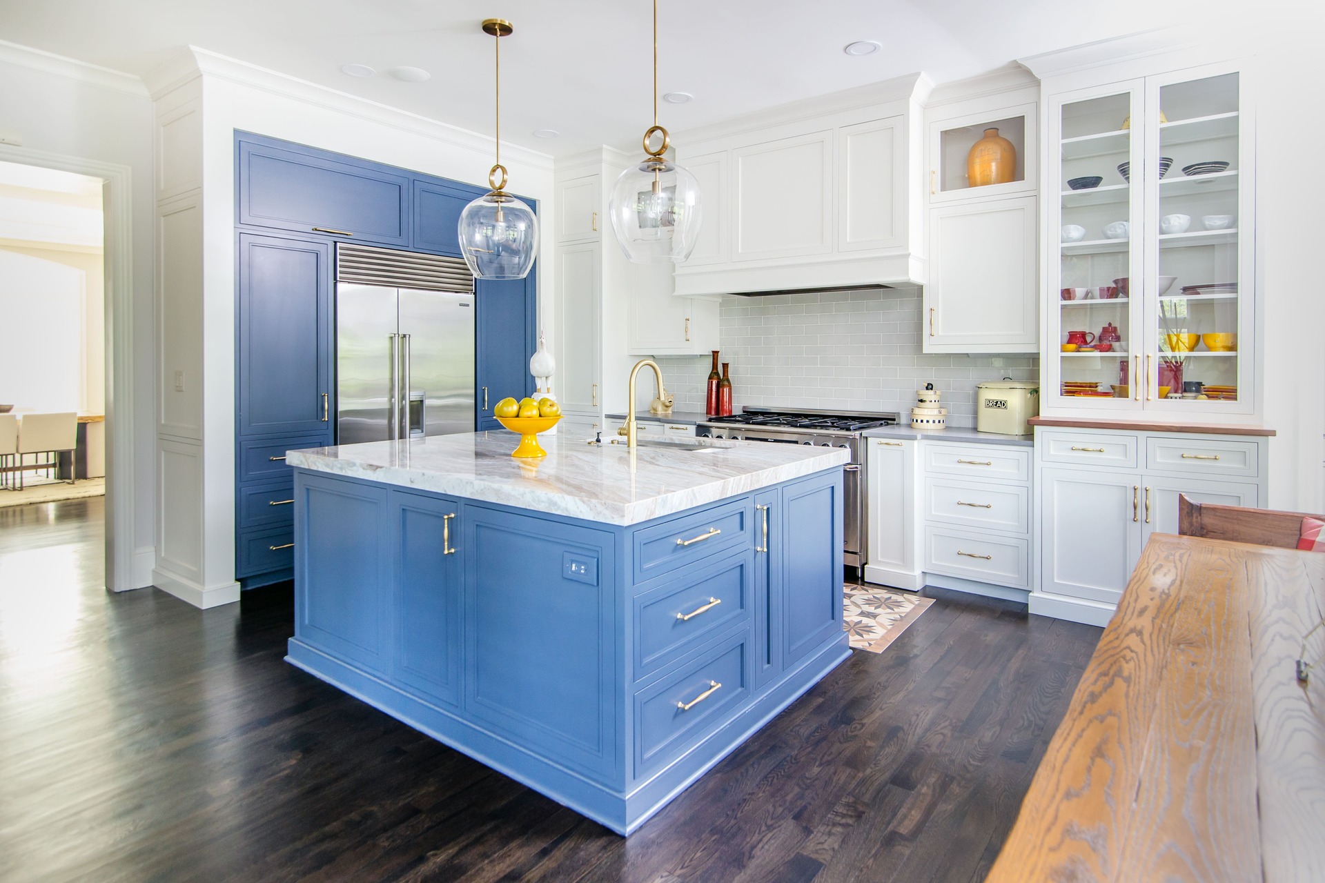 A kitchen with white and blue cabinetry and glass front doors