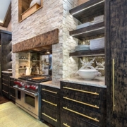 A kitchen with black cabinetry and a stone fireplace above the stove