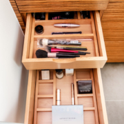 A bathroom with a double divider drawer pulled open with makeup organized all inside