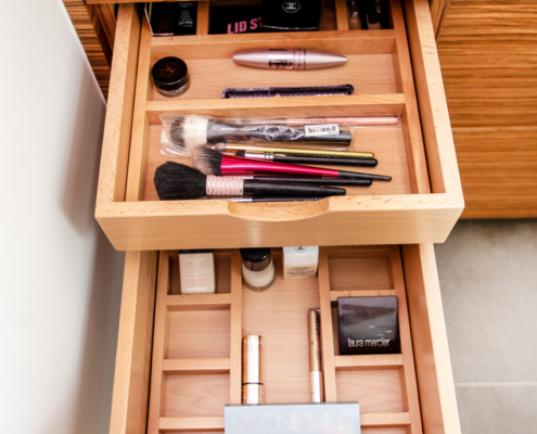 A bathroom with a double divider drawer pulled open with makeup organized all inside