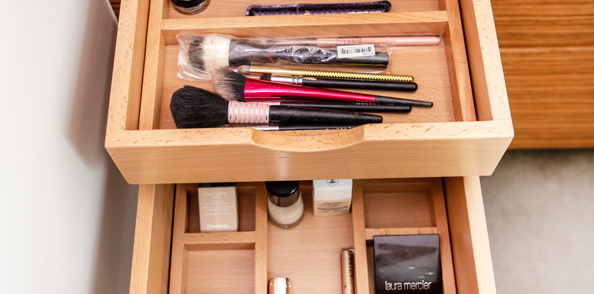 A bathroom with a double divider drawer pulled open with makeup organized all inside