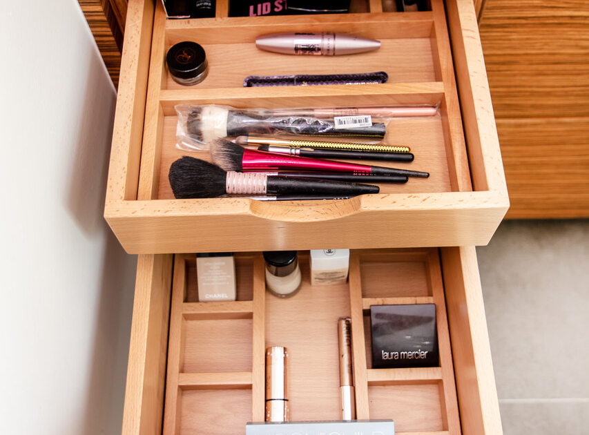 A bathroom with a double divider drawer pulled open with makeup organized all inside