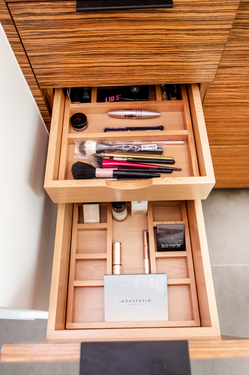 A bathroom with a double divider drawer pulled open with makeup organized all inside