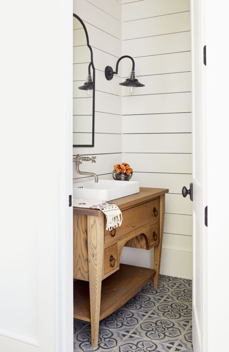 A guest bathroom with a reclaimed bathroom vanity and tile design flooring