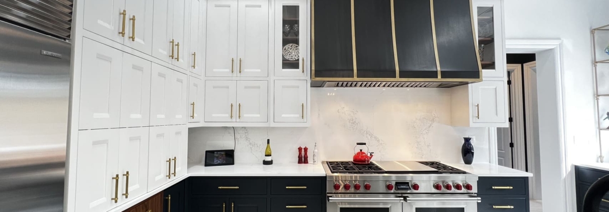 White and blue kitchen cabinets with gold accents and a large hood
