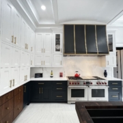 White and blue kitchen cabinets with gold accents and a large hood