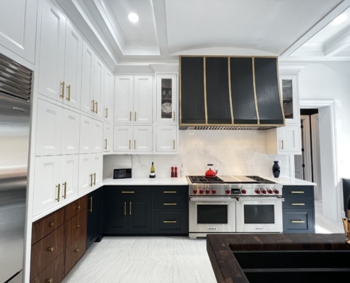 White and blue kitchen cabinets with gold accents and a large hood