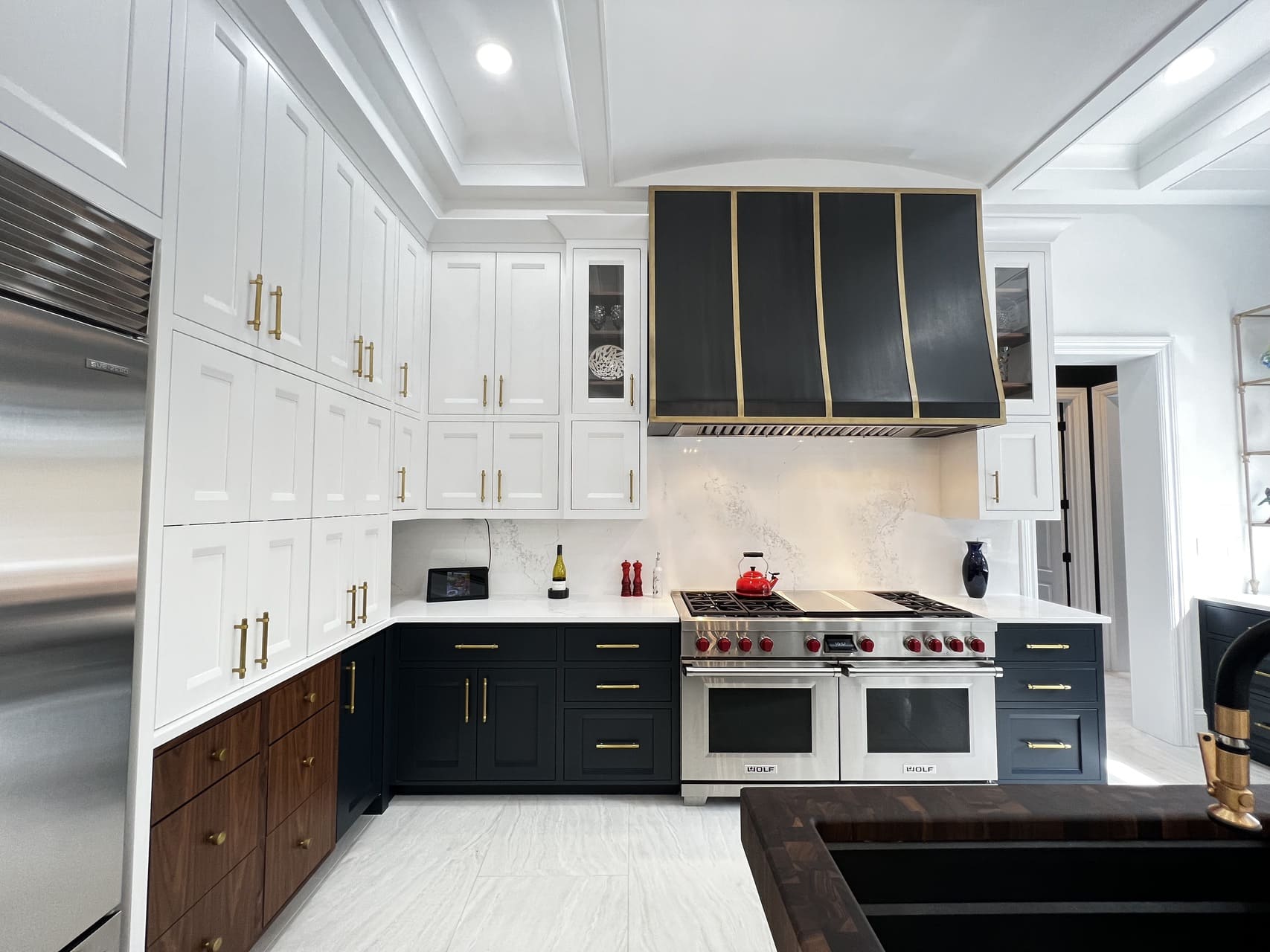 White and blue kitchen cabinets with gold accents and a large hood