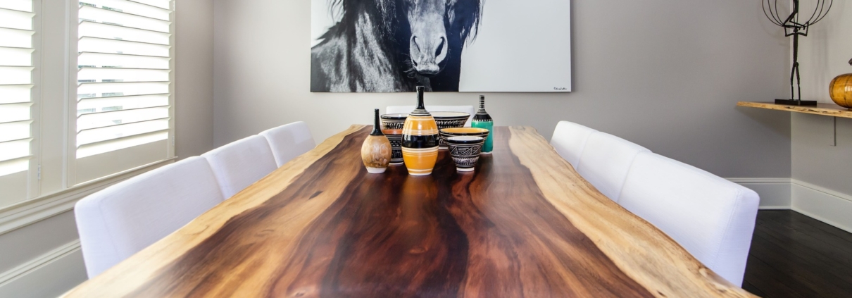 A live edge wooden dining room table with artwork and decor pieces