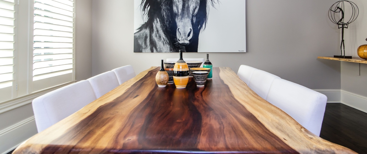 A live edge wooden dining room table with artwork and decor pieces