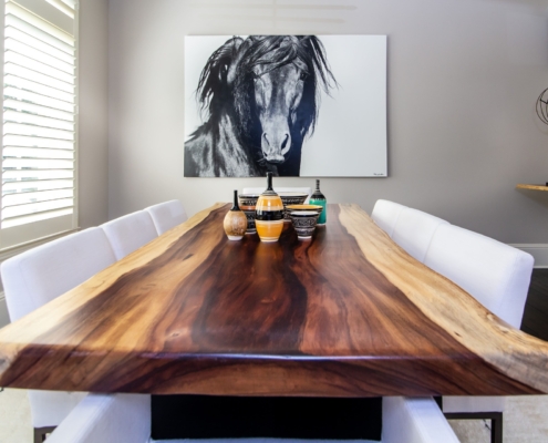A live edge wooden dining room table with artwork and decor pieces