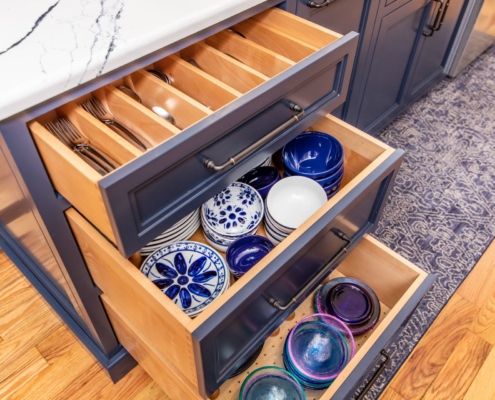 blue kitchen island with dishware in drawers